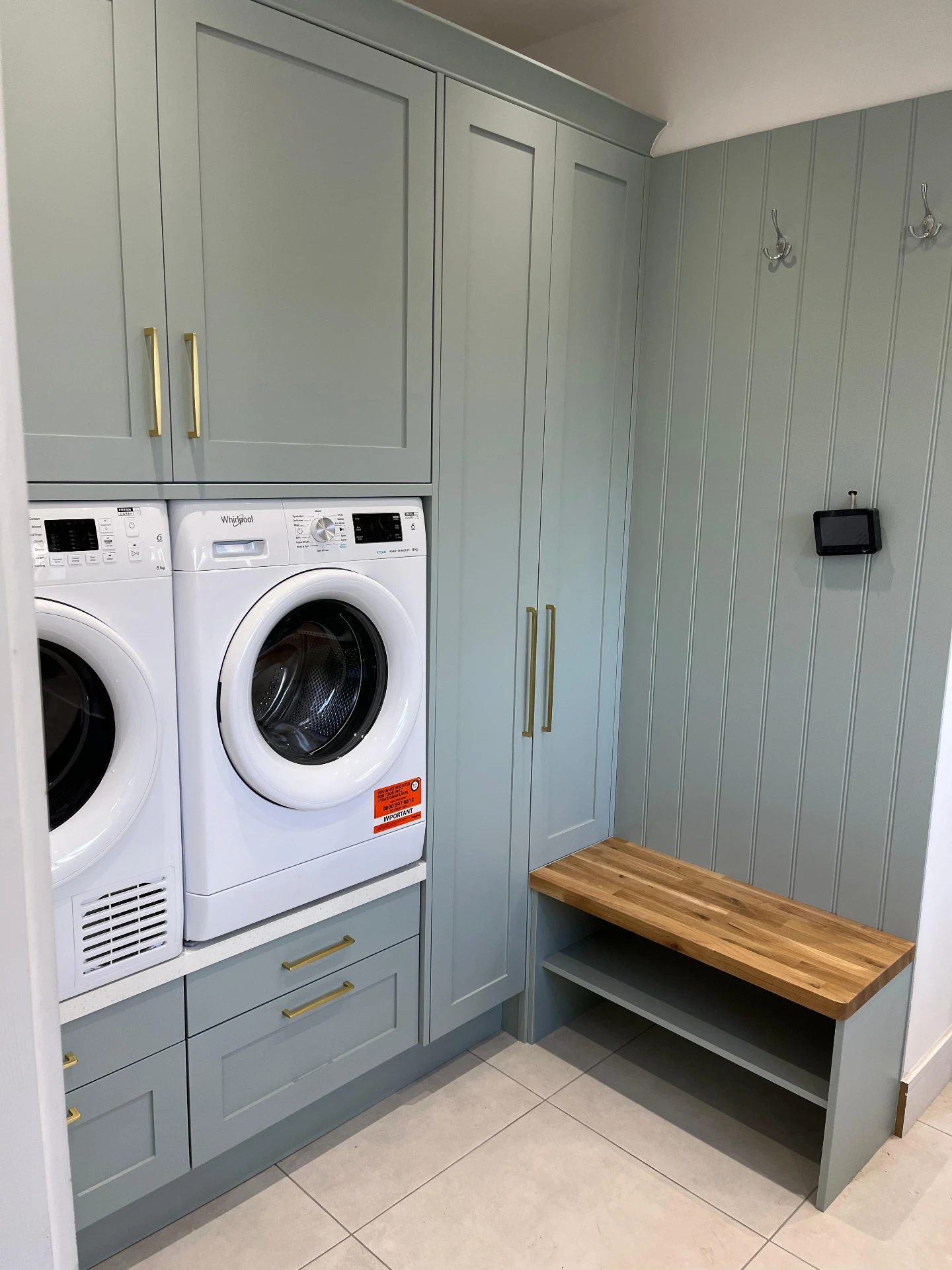 Sage utility room bench area with fitted laundry room storage.
