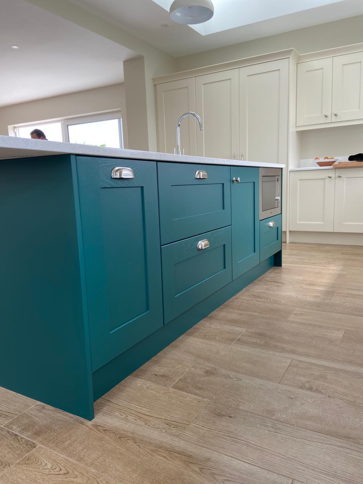 Close detail of teal shaker-style kitchen island cabinetry with brushed cup handles.